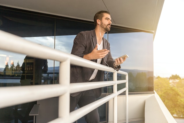 Person leaning against a balcony having a phone conversation on white earbuds